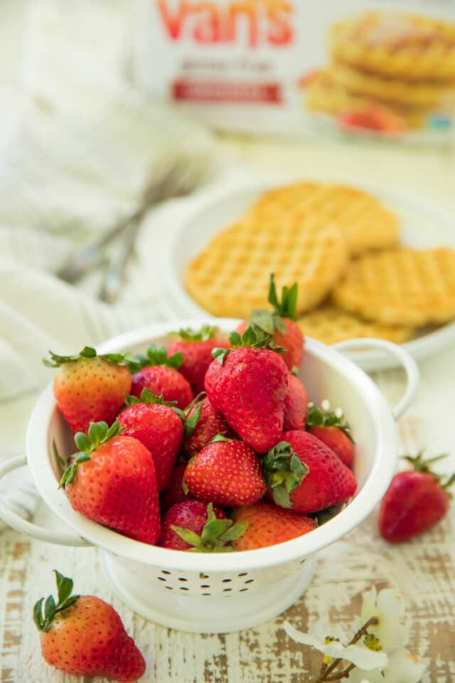 small white colander filled with fresh strawberries