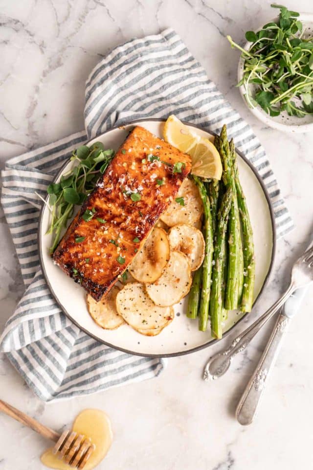 honey glazed salmon, asparagus and roasted potato served on a plate with lemon wedges