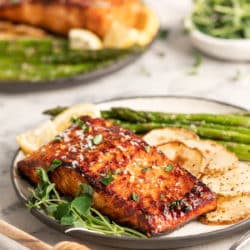 serving of honey glazed salmon plated with asparagus and potatoes