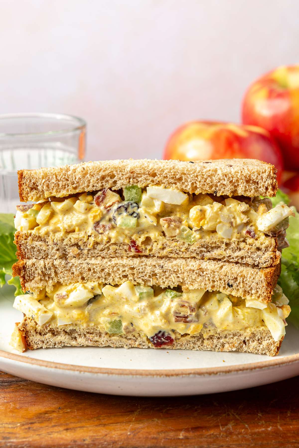 Curried egg salad sandwich cut in half on a white plate.