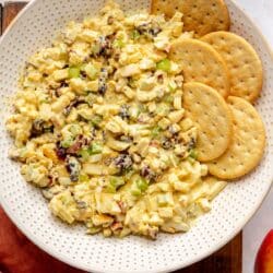 Curried egg salad in a white bowl with round crackers.