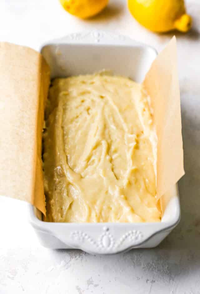lemon pound cake batter in a loaf pan lined with parchment paper