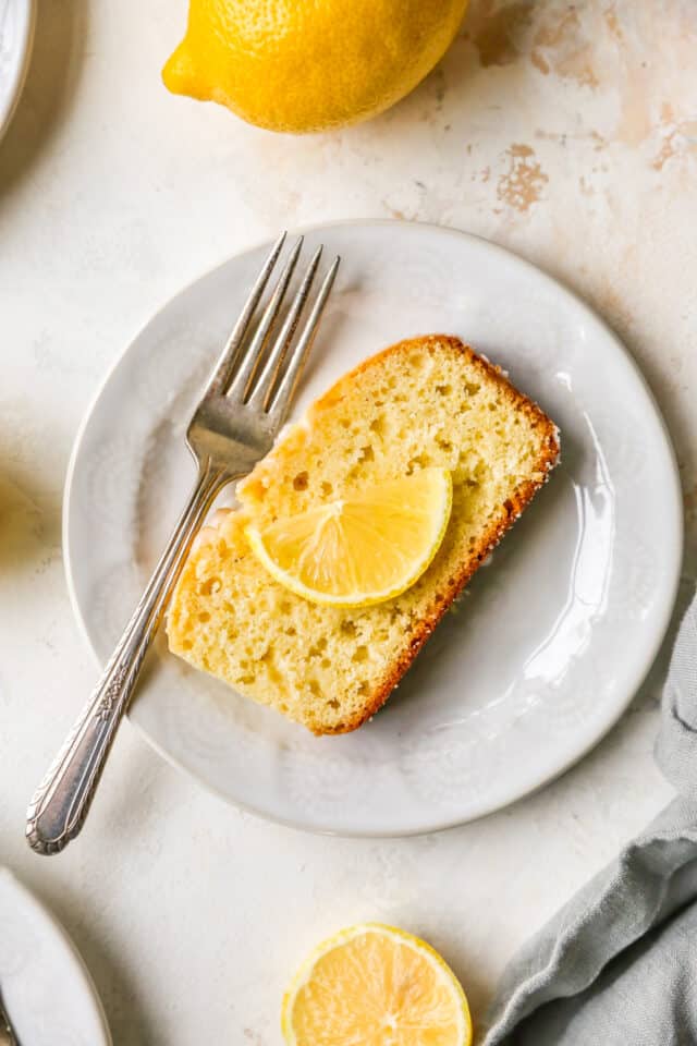 slice of lemon cake garnished with a slice of lemon on a small white plate