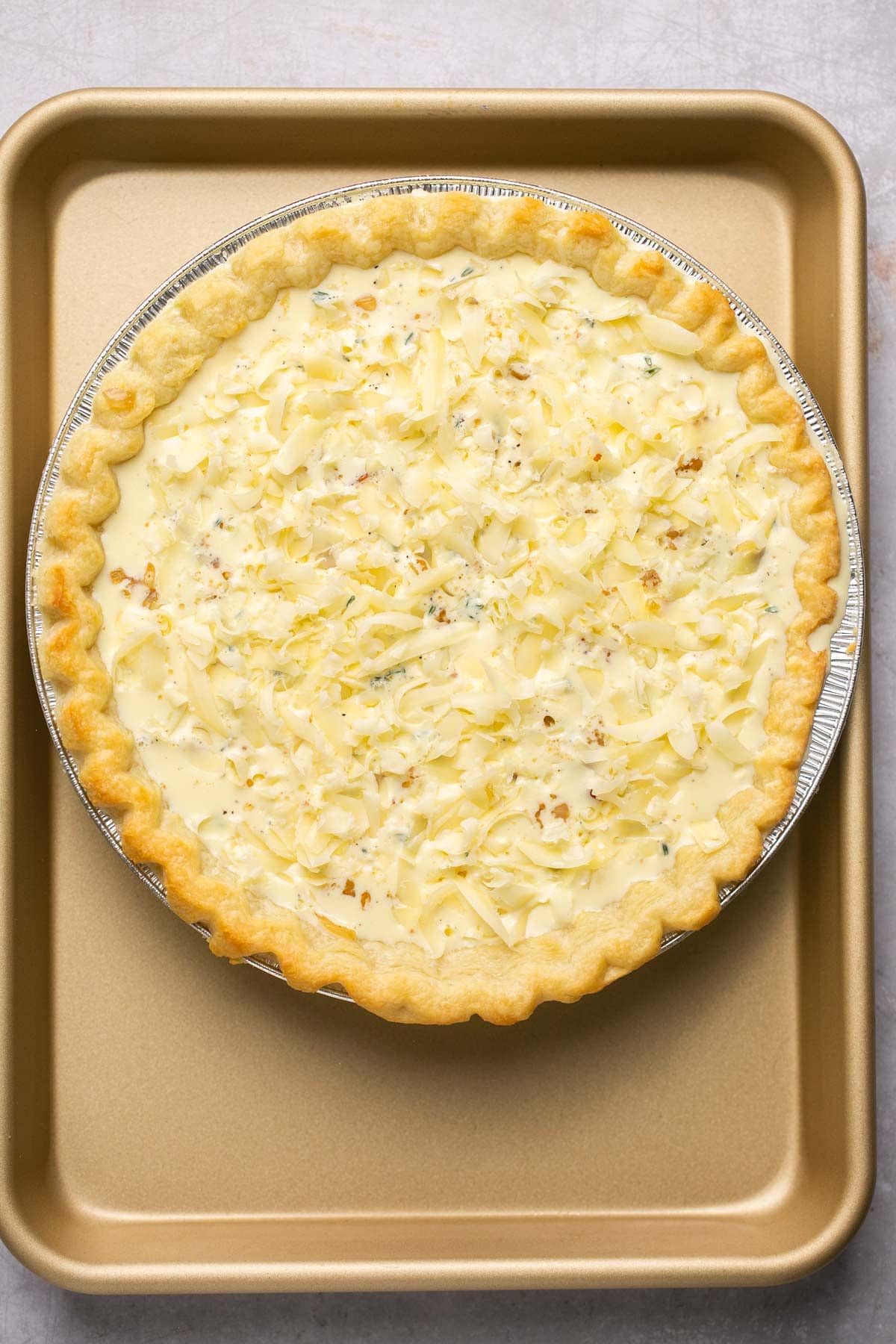 Quiche sprinkled with cheese before baking.