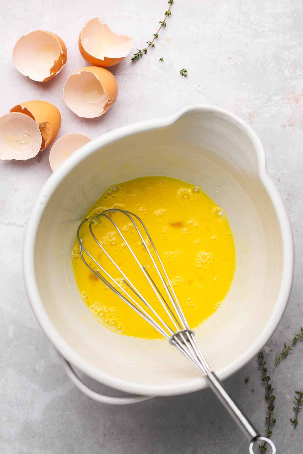 Whisking eggs and egg yolks in a large bowl.