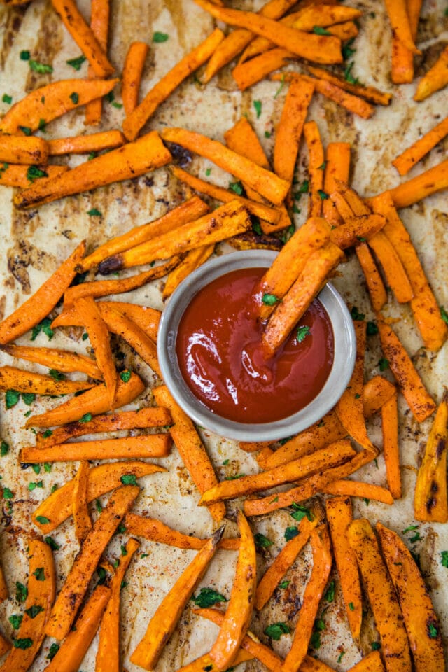 sweet potato fries on a baking pan with a small bowl of ketchup