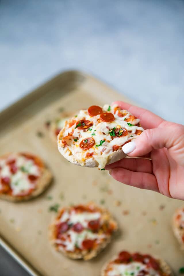 Woman's hand holding up an English Muffin Pizza