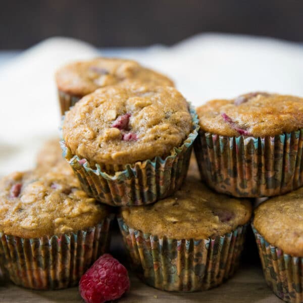 raspberry oatmeal muffins stacked on a wooden cutting board