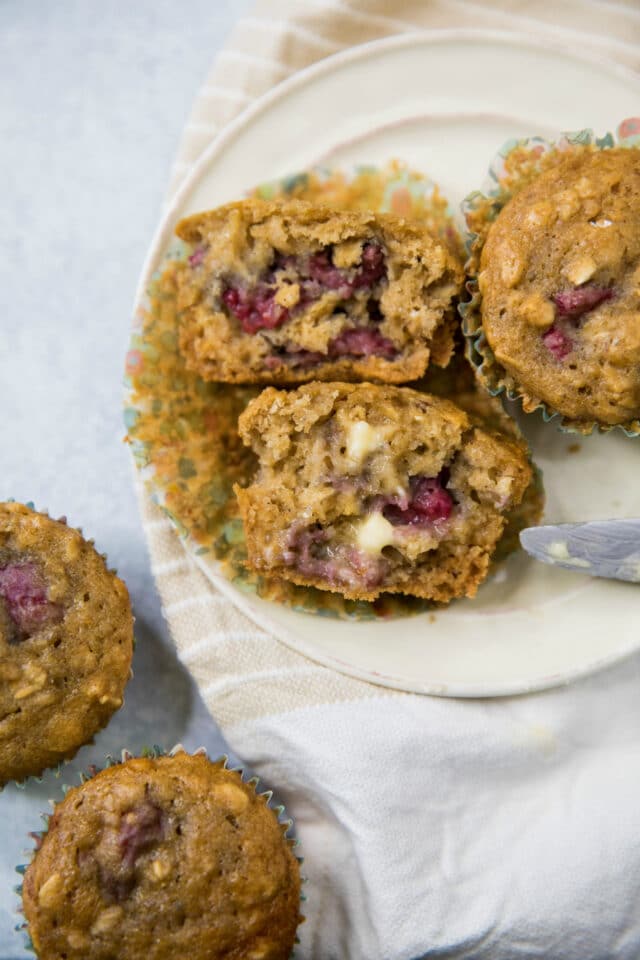 raspberry muffins on a plate with one cut in half and topped with butter