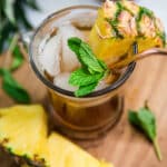 glass of iced tea with sprigs of mint and pineapple chunks