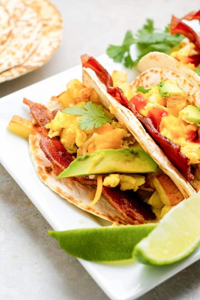 Breakfast tacos with eggs, bacon and sliced avocado. 