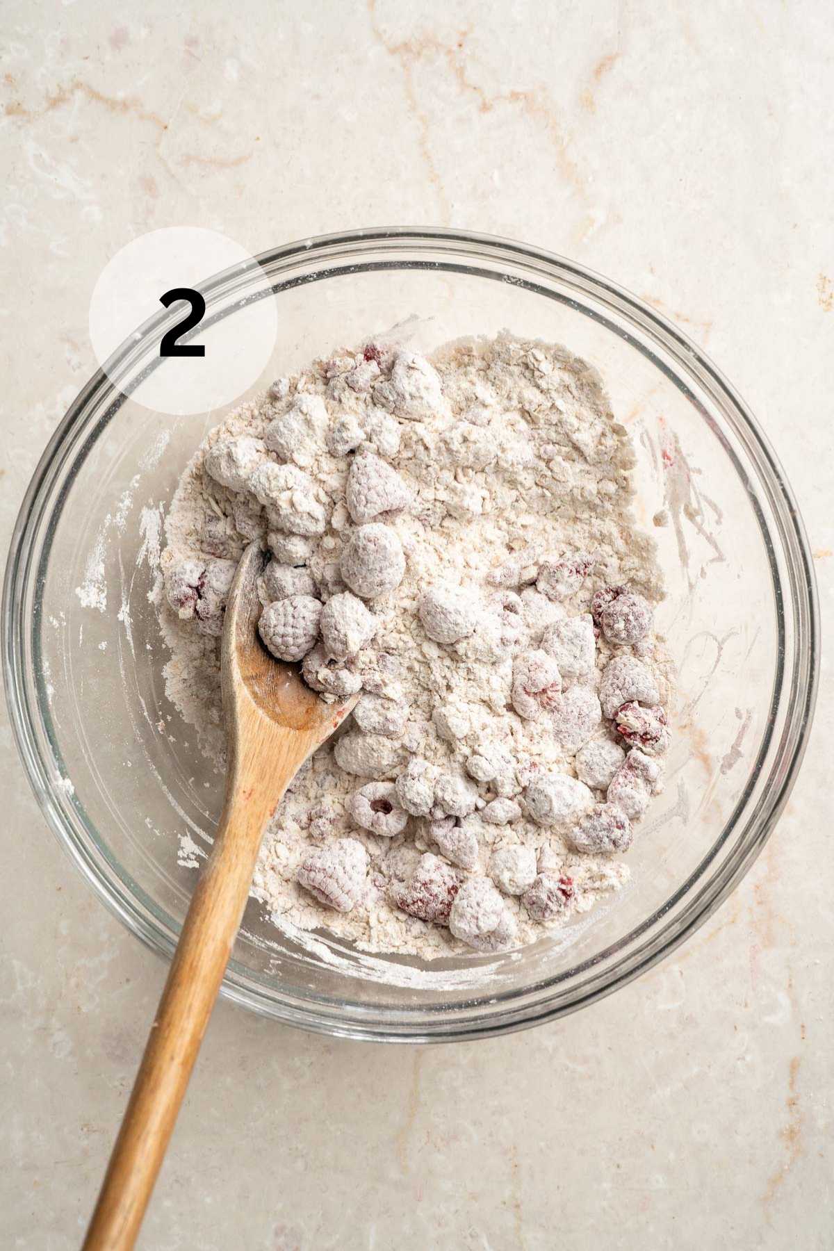 Tossing raspberries in a flour mixture in a bowl.