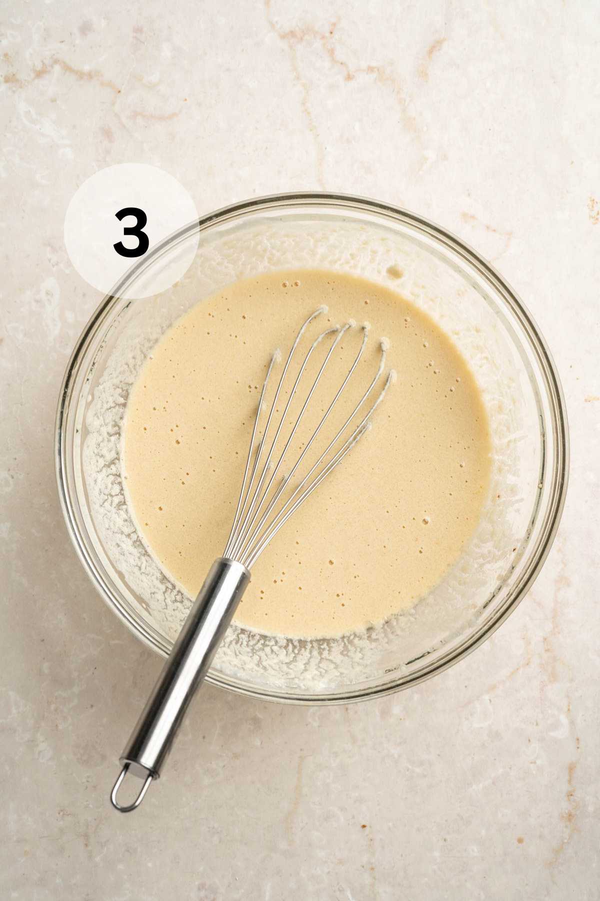 Whisking wet ingredients in a large glass bowl.