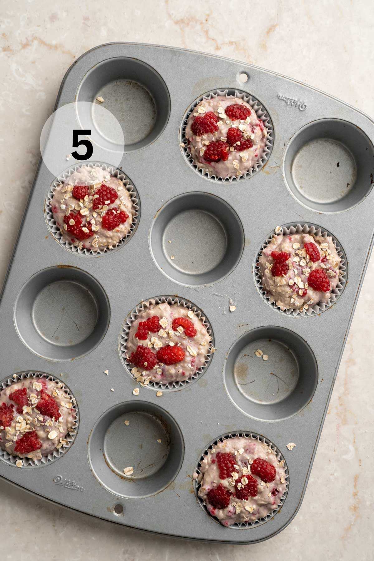 Raspberry muffin batter in a muffin pan.