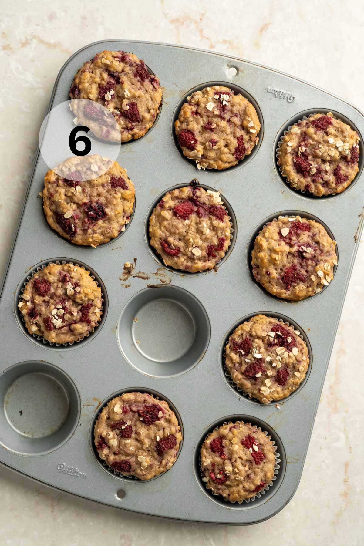 Baked raspberry oat muffin in a muffin pan.