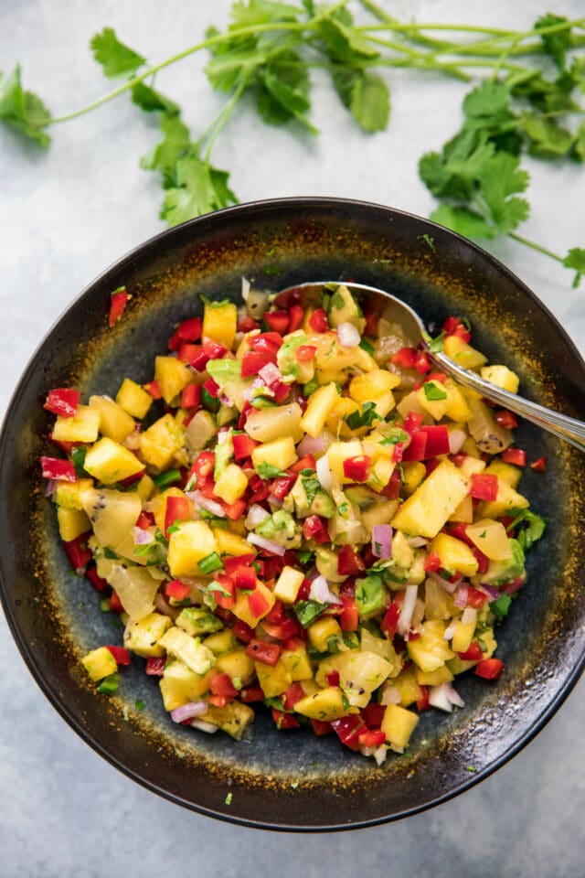 ingredients for kiwi pineapple salsa mixed in a black colored bowl