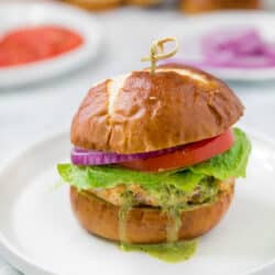 turkey burger with a pretzel bun topped with lettuce, tomato, red onion