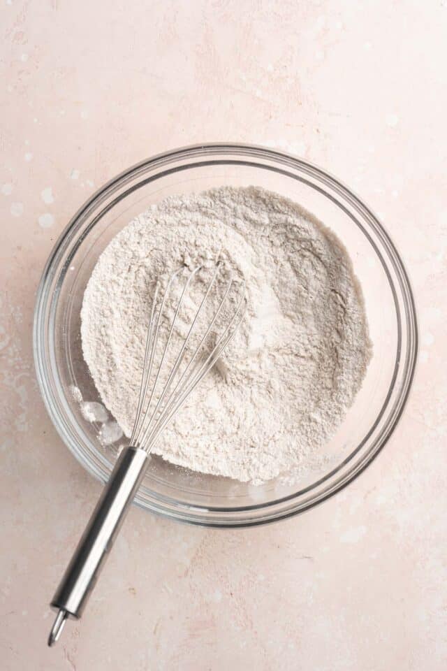 Whisking dry ingredients in a large glass bowl.