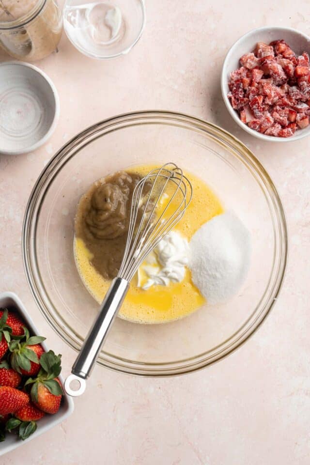 Combining eggs with mashed banana in a large glass bowl.