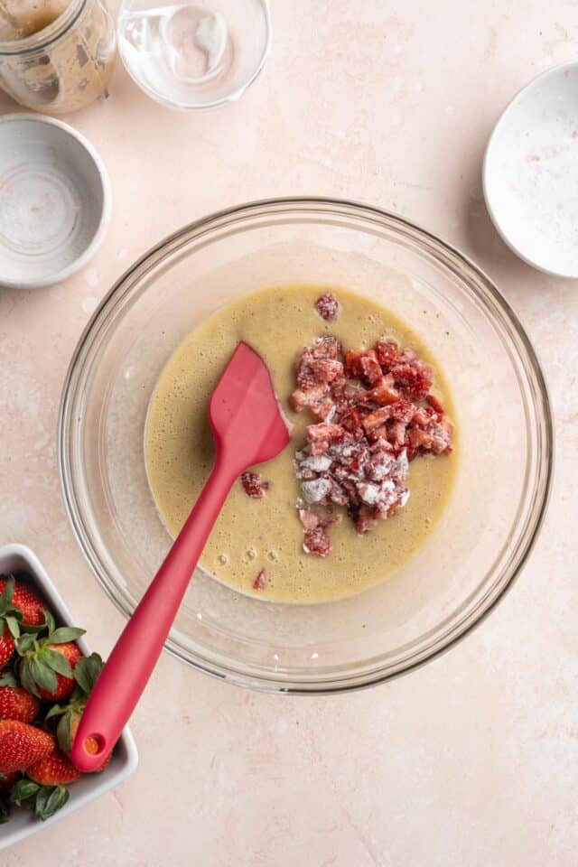 Stirring diced strawberries into bread batter.