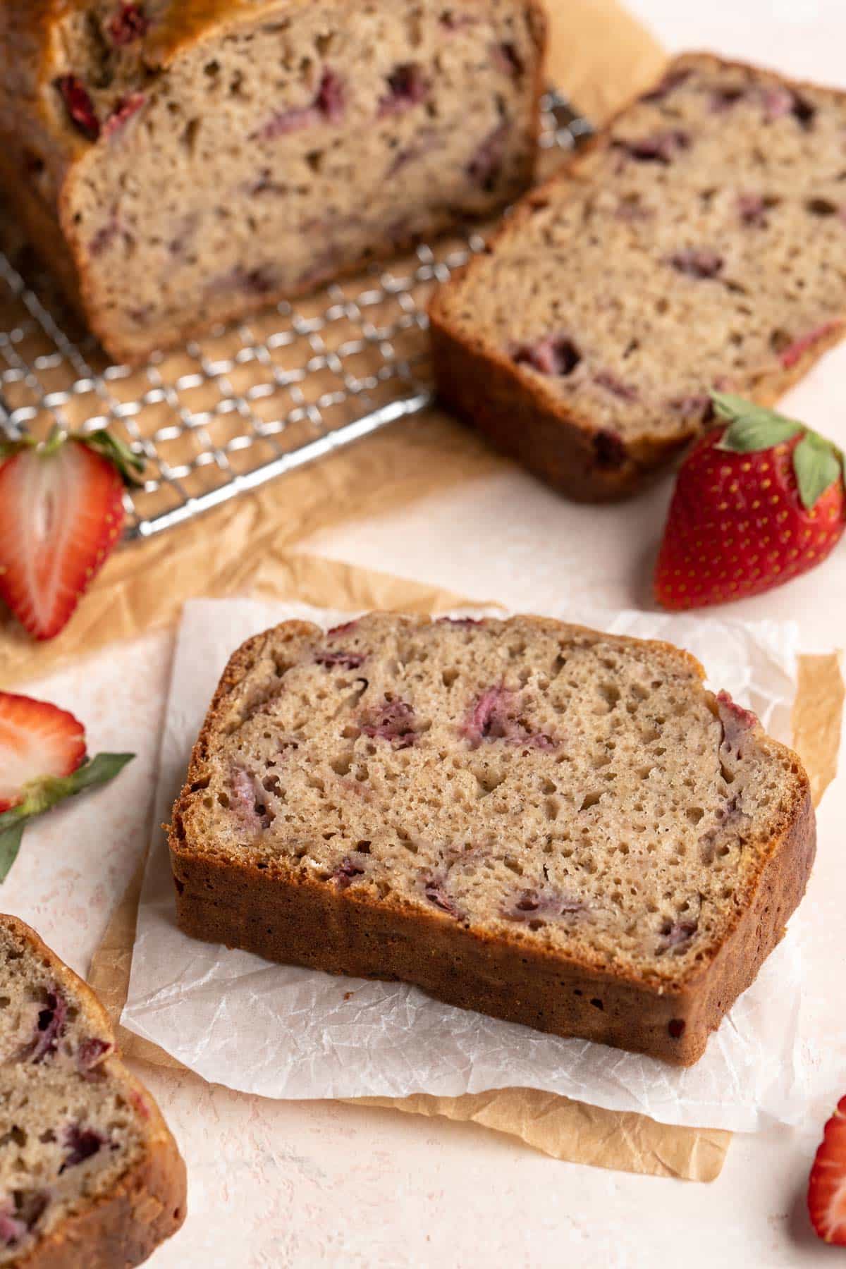Slices of strawberry banana bread on parchment paper.