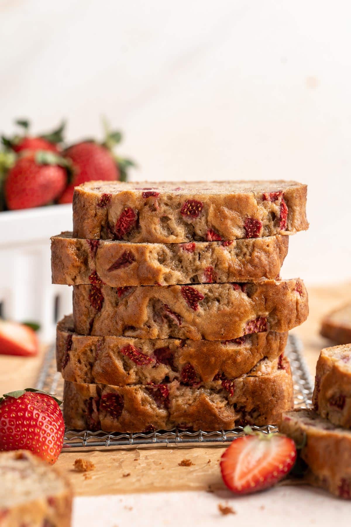 Slices of bread with strawberries stacked near fresh strawberries.