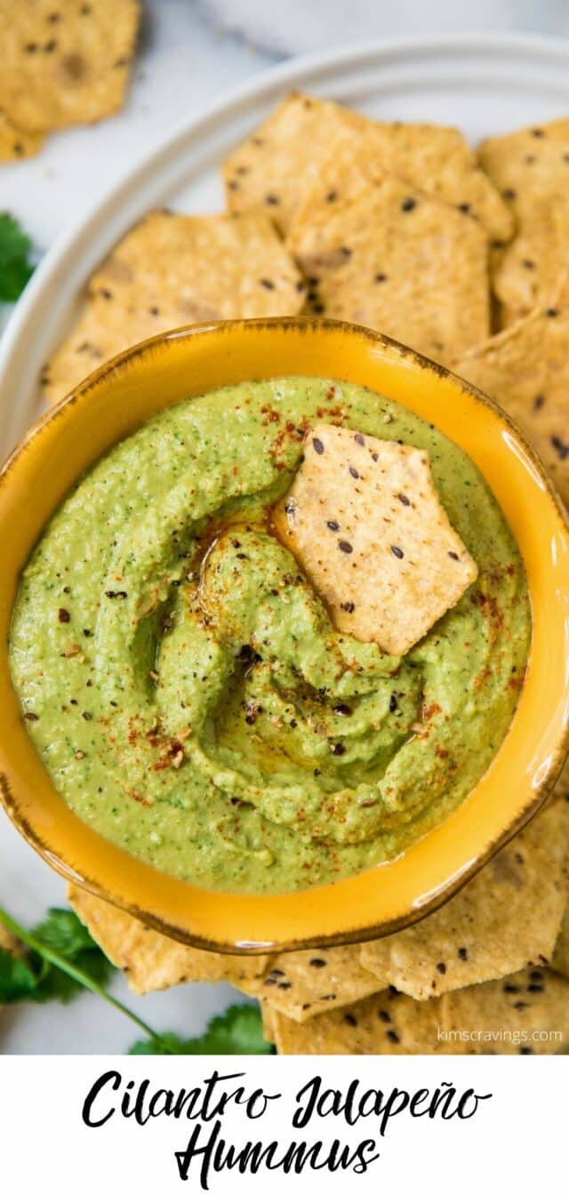 a chip dipped in a green hummus appetizer