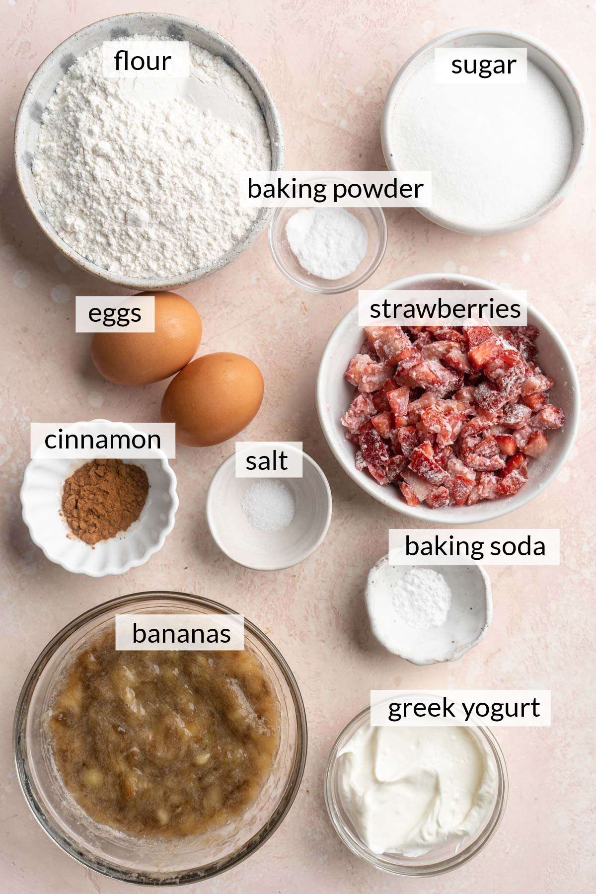 Bowl of floured strawberries, flour, sugar, greek yogurt, mashed bananas, cinnamon and salt.