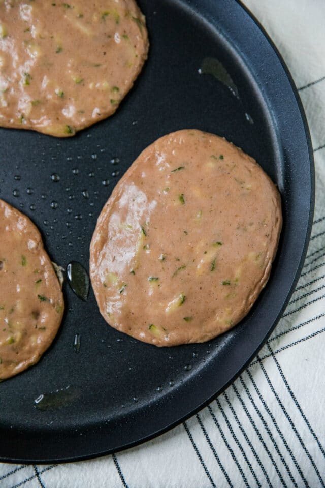 cooking zucchini pancakes on a large skillet