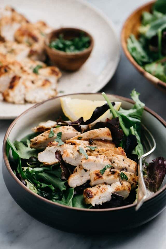 grilled chicken served over a bowl full of greens