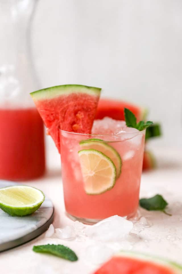 vodka watermelon cocktail in a small glass with a watermelon slice and lime slices