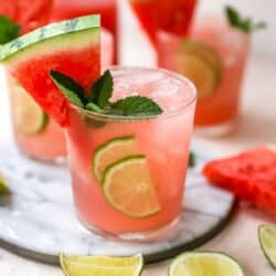 Watermelon cocktail garnished with a watermelon wedge, mint and lime.