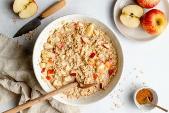 stirring oats and apple chunks with milk in a large bowl