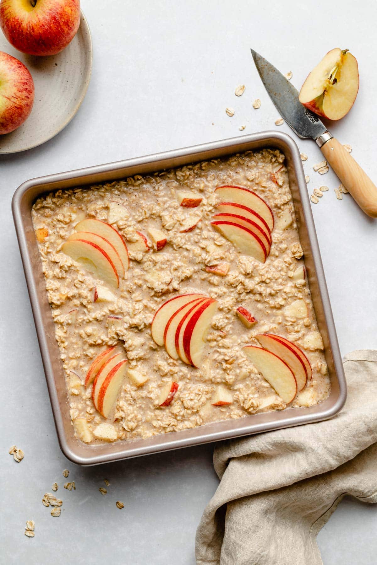 adding oatmeal and apple slices to a baking pan