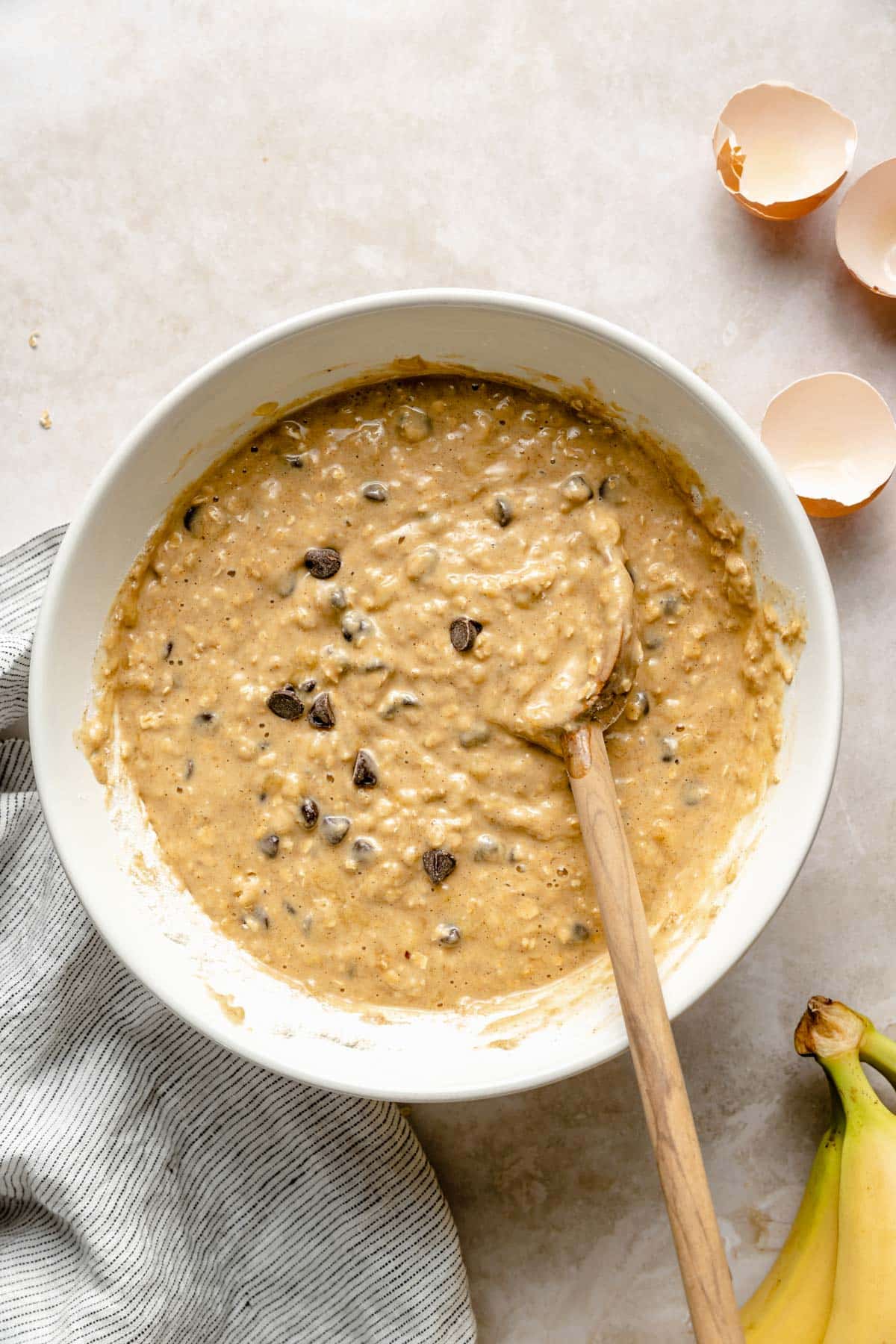 Mixing chocolate chips into banana bread batter in a large bowl.
