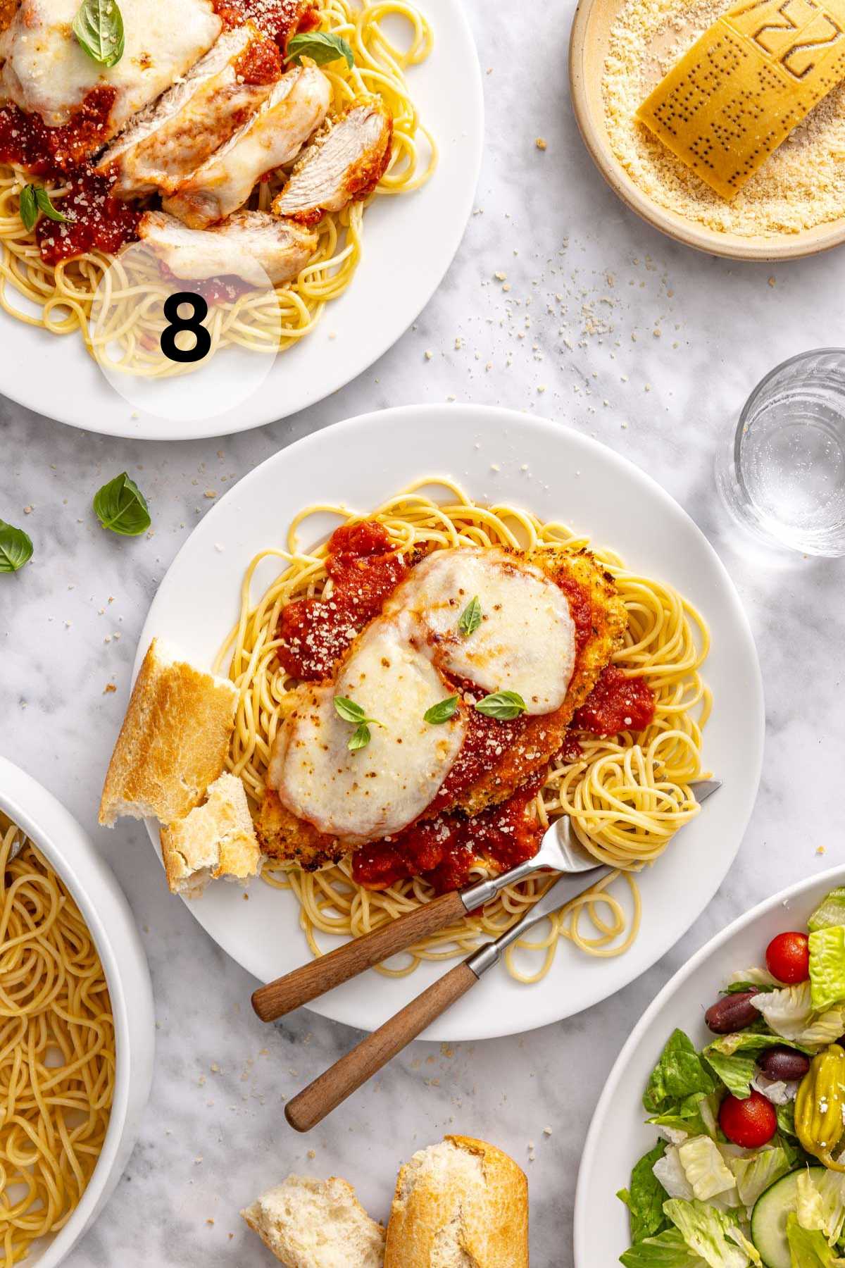 Baked chicken parmesan served with spaghetti, bread and a salad.