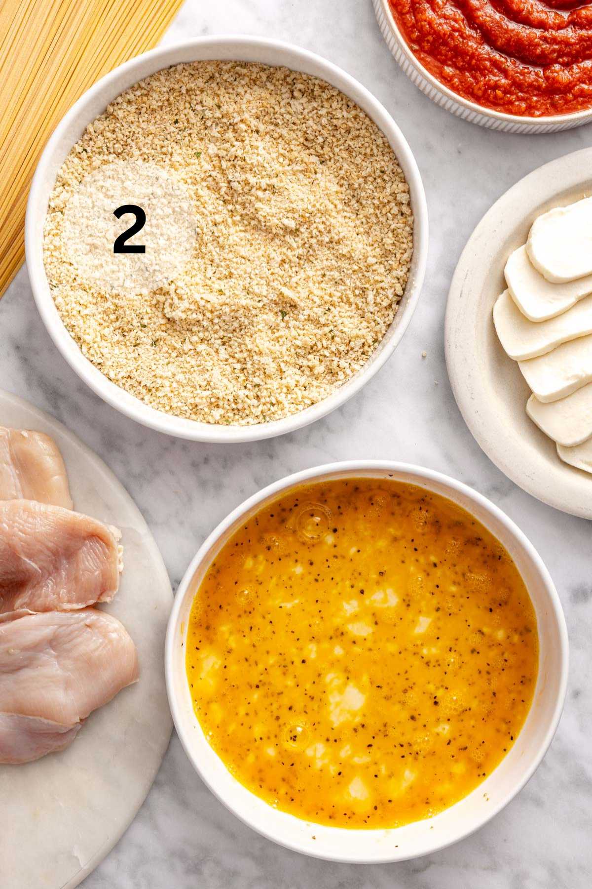 One bowl with egg mixture and one bowl with breadcrumb mixture.