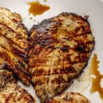 Juicy grilled chicken breasts on a white plate.