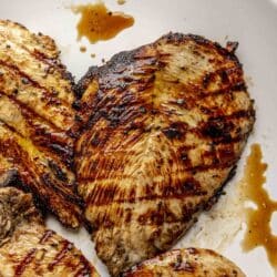 Juicy grilled chicken breasts on a white plate.