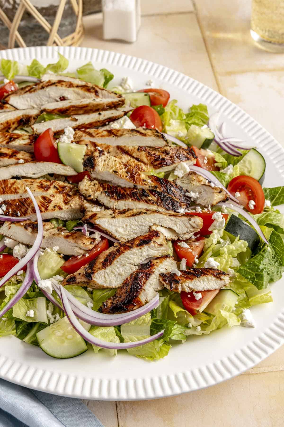 Grilled chicken salad on a large white serving plate.
