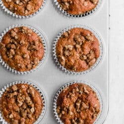 Applesauce muffins with a cinnamon oat topping in a muffin pan.