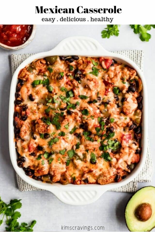 Mexican casserole in a white baking dish served with salsa and avocado