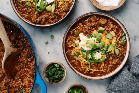 bowls filled with beef chili and topped with sour cream and cheese