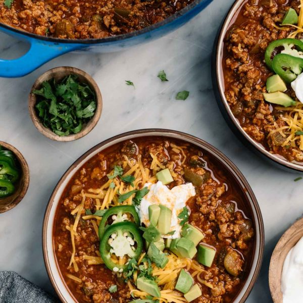 Beef chili served in bowls with cheese, sour cream and avocado.