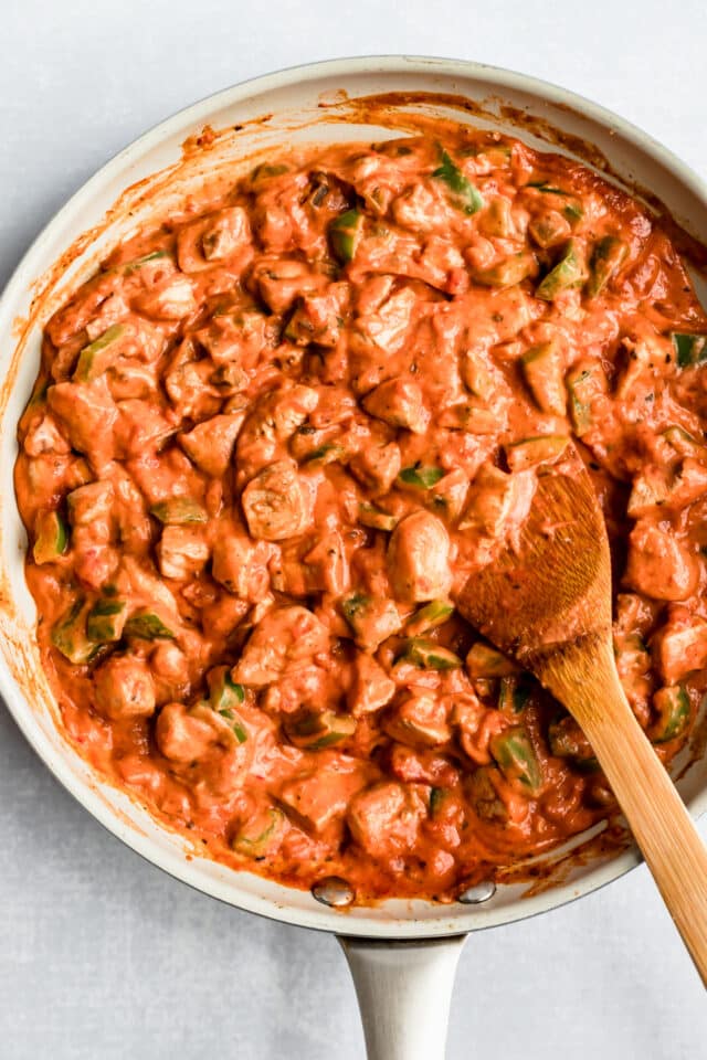 chicken cooking in a creamy red sauce in a large skillet