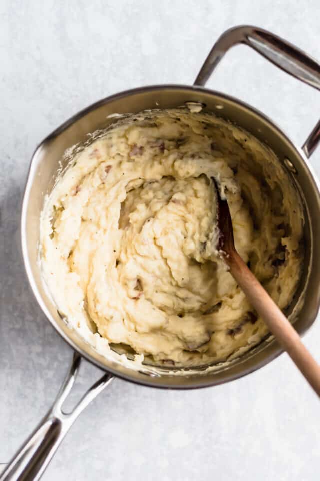 wooden spoon stirring mashed potatoes in a pot