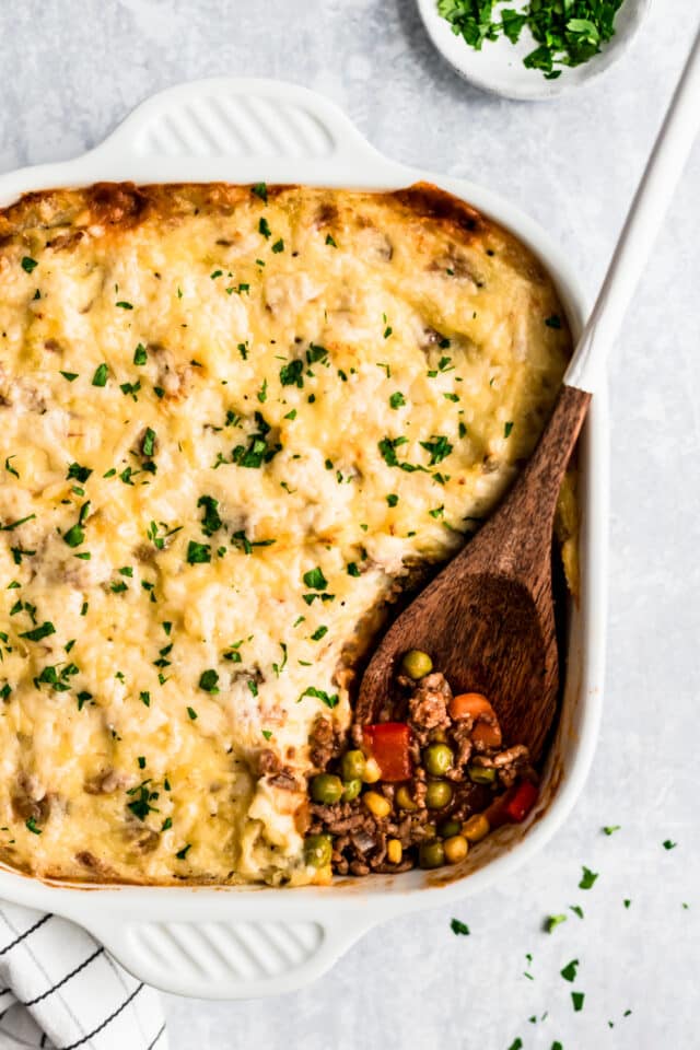 Shepherd's Pie in a white baking dish with a wooden spoon