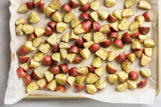 Placing potatoes on a sheet pan to roast.