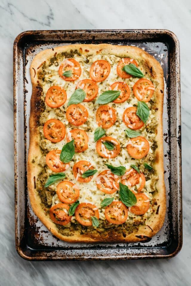 Breakfast Pizza cooked on a baking sheet and topped with tomatoes and basil