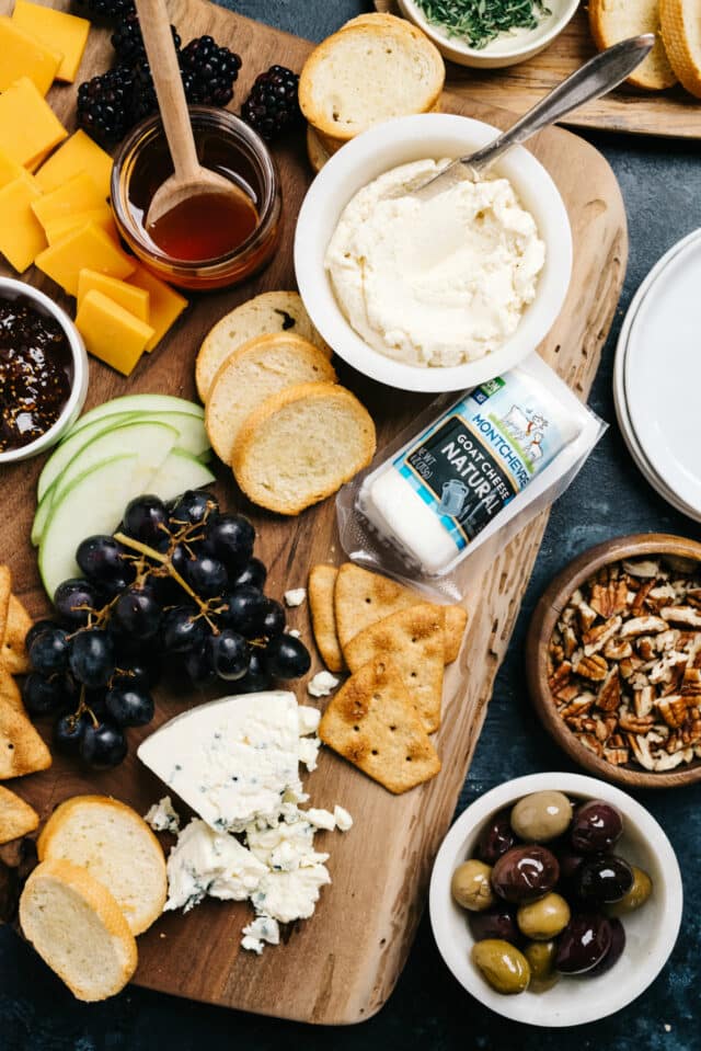 cheese board with blue cheese, goat cheese, crackers, grapes and apple slices